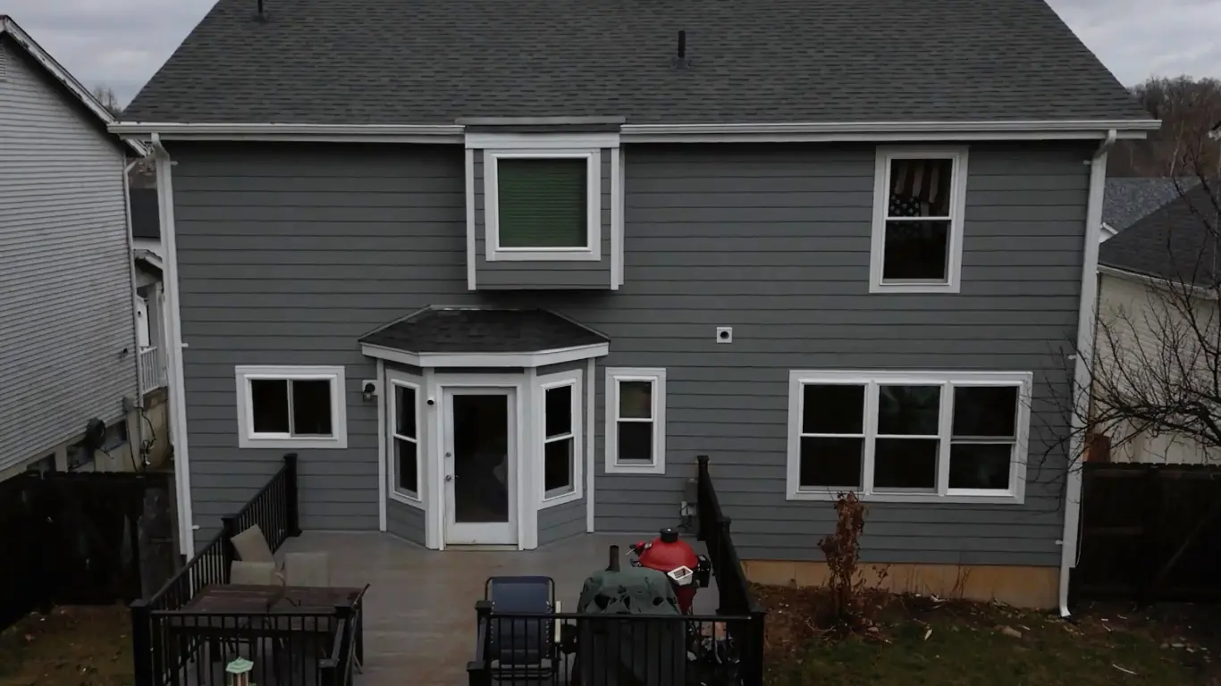 Gray house with back patio and windows.