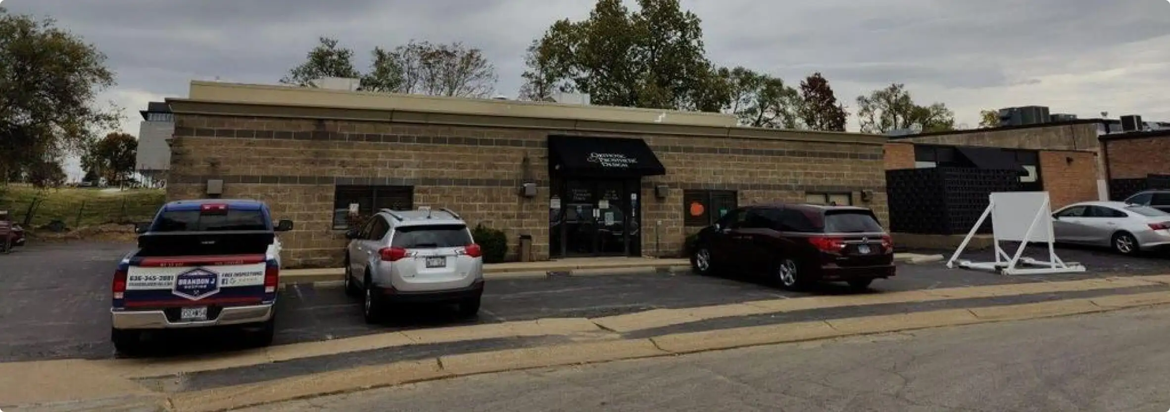 Brick building with parked cars in front.